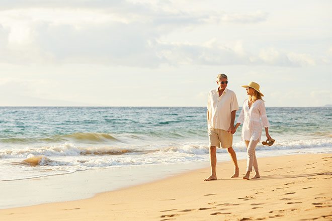 Coppia di anziani che passeggiano sulla spiaggia