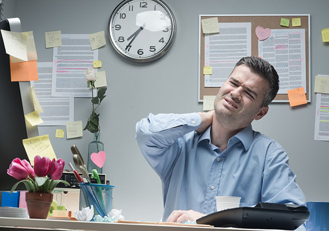 uomo in ufficio con dolori alla cervicale